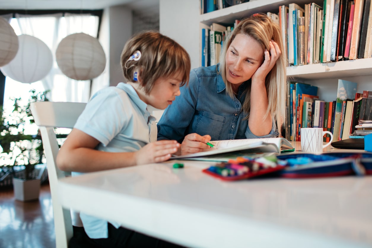 Special education teacher helps student with hearing impairment, cochlear implant. Teaching students with special needs.